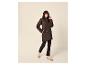 Frau in dunkler Steppjacke, schwarzen Jeans und beigen Sneakern.