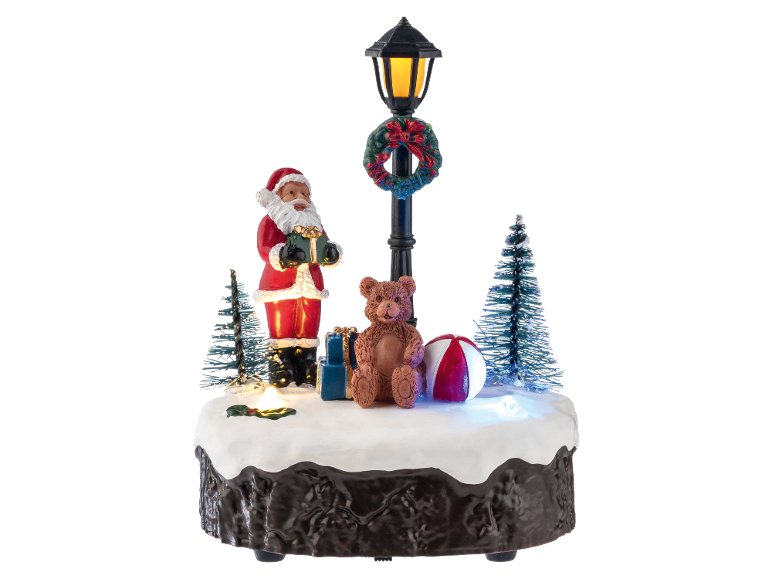 Beleuchtete Weihnachtsdekoration mit Weihnachtsmann, Teddybär und Straßenlaterne auf Schnee.