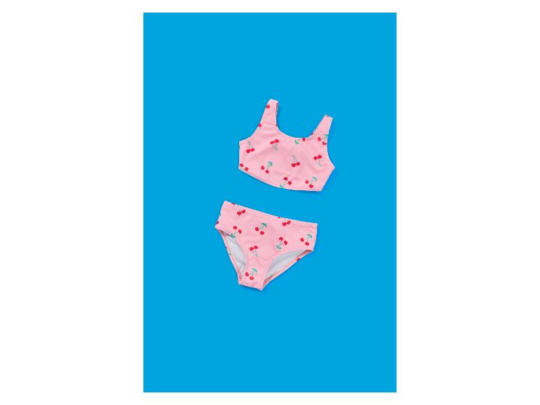 Rosa Kinder-Bikini mit Kirschmuster auf blauem Hintergrund.