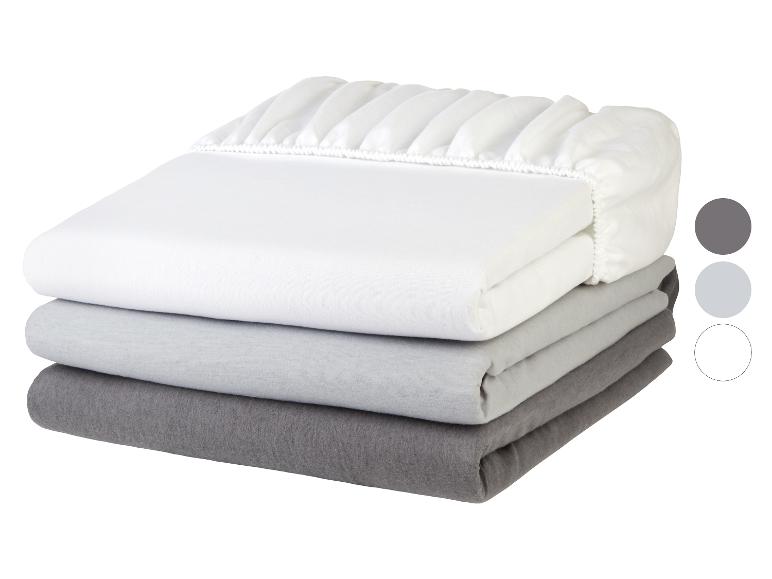 Drei gefaltete graue und weiße Spannbettlaken in einem Stapel, mit Gummizug.