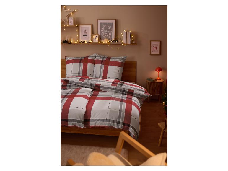 Ein gemütliches Schlafzimmer mit karierter Bettwäsche, Lichterketten und winterlicher Wandkunst.