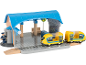 Spielzeug-Bahnhof mit gelbem Zug und Schaffnerfigur.