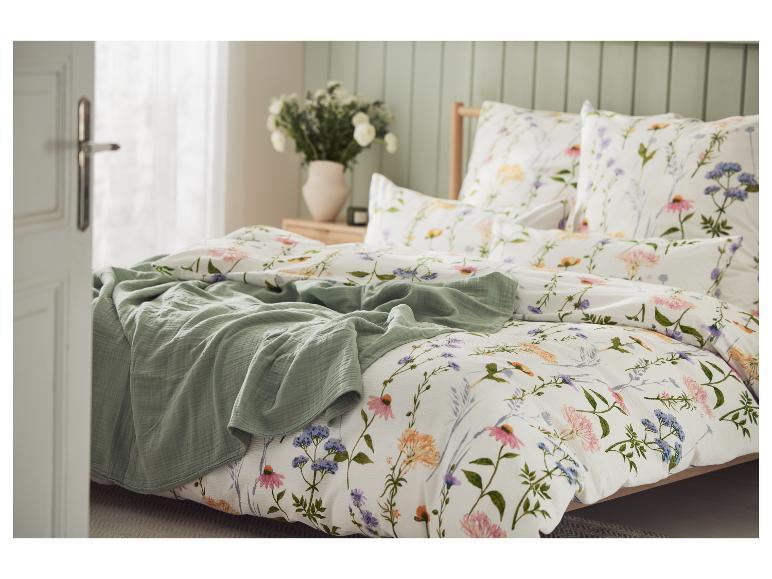 Schlafzimmer mit weißer Bettwäsche mit Blumenmuster und grüner Decke