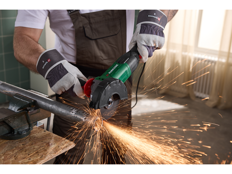 Handwerker schneidet ein in einen Schraubstock eingespanntes Metallrohr mit einem Winkelschleifer.