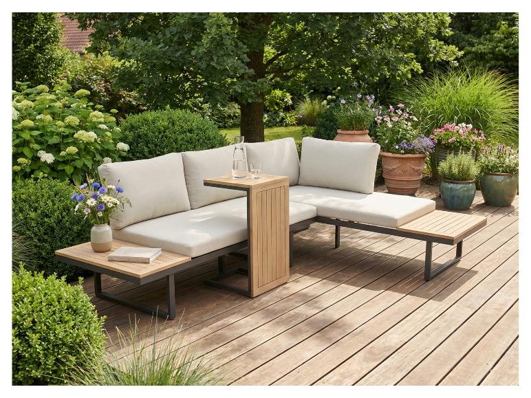 Modulares Gartensofa mit hellen Kissen und Holztischen auf einer Holzterrasse, umgeben von Pflanzen.