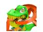 Hot Wheels Spielset mit grünem Dinosaurier und oranger Strecke, mit einem Rennwagen.