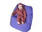 Glückliches Baby im roten Overall liegt auf einem lila Sitzsack.