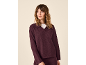 Frau in bordeauxfarbenem Polo-Pullover und passender Hose, blickt zur Seite.