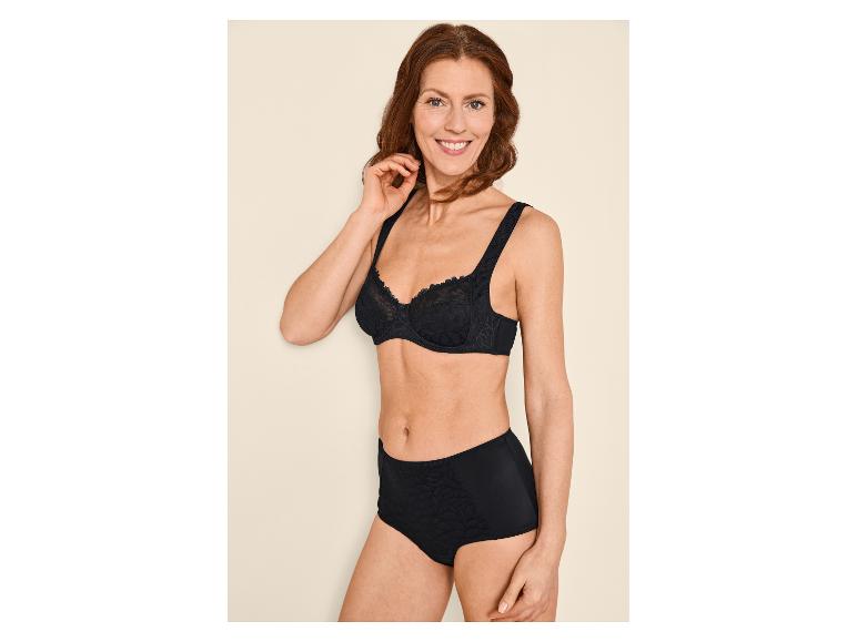 Lächelnde Frau in schwarzem BH und Slip mit Blumenmuster.