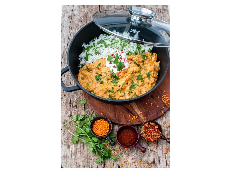 Hähnchen-Curry mit Reis, Koriander und Gewürzen in einem ELO Topf auf einem Holzbrett.