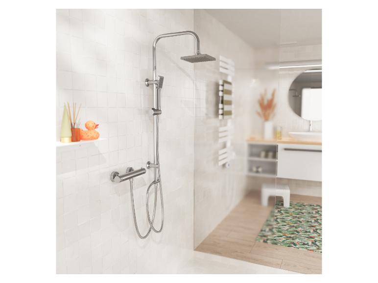 Verchromtes Duschset mit Regendusche und Handbrause, auf weißen Fliesen im Badezimmer.