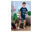 Junge in blauem T-Shirt und Shorts mit Gaming-Motiv, hält einen grünen Ball im Schlafzimmer.