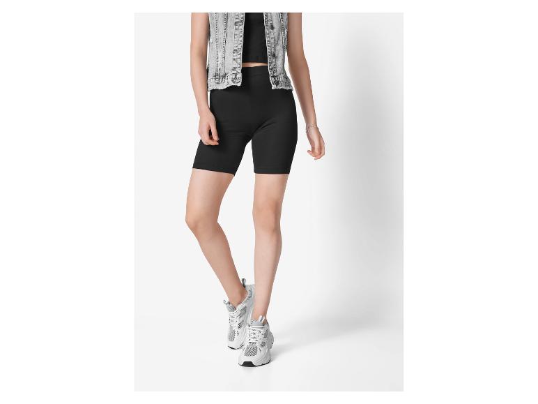 Modell trägt schwarze Radlerhose und weiße Sneaker.