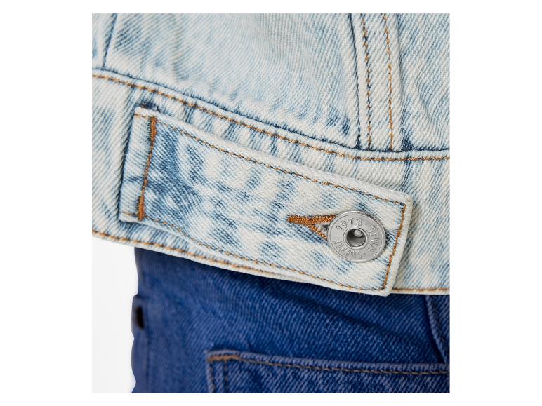 Nahaufnahme einer Jeansjacke mit einem Knopf mit dem Logo 'Superdry'