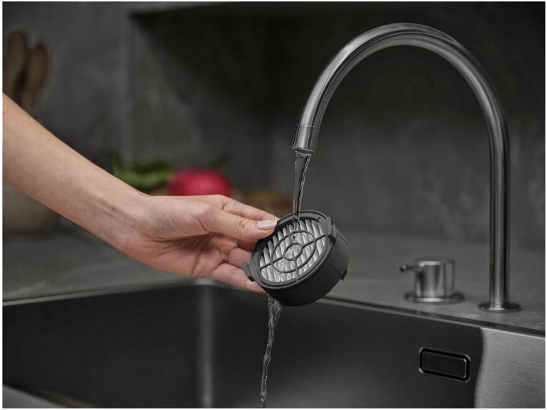 Hand wäscht Filter unter Wasserhahn in Küchenspüle.