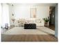 Modernes Wohnzimmer mit beigem Sofa, schwarzem Couchtisch und hellem Teppich.