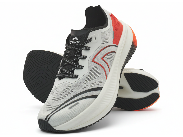 Paar weiße und rote Sportschuhe mit schwarzen Schnürsenkeln und Sohlen, einer steht aufrecht.