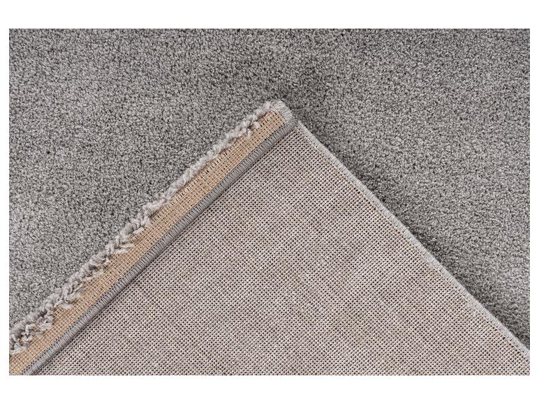 Grauer Teppich mit umgeklappter Ecke, die die Unterseite und den Rand zeigt.