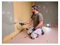Mann streicht Wand, beleuchtet von LIVARNO® Arbeitslicht »The Painter«.