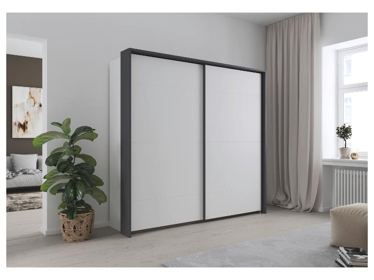 Weißer Schwebetürenschrank mit dunkelgrauem Rahmen in einem hellen Schlafzimmer.