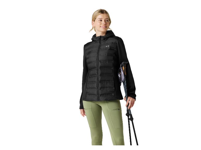 Frau in schwarzer Steppjacke, olivgrüner Hose und mit Wanderstöcken.