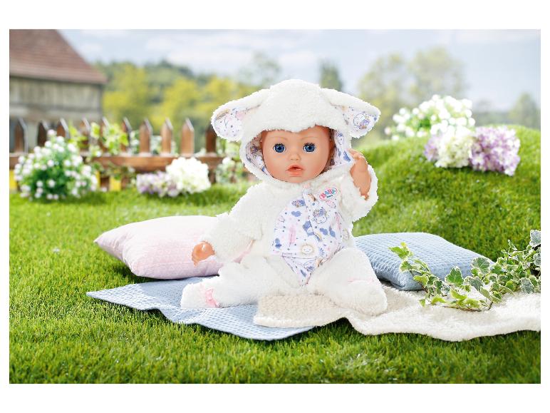 BABY born Puppe im Lammkostüm auf einer Decke im Gras mit Kissen und Blumen.