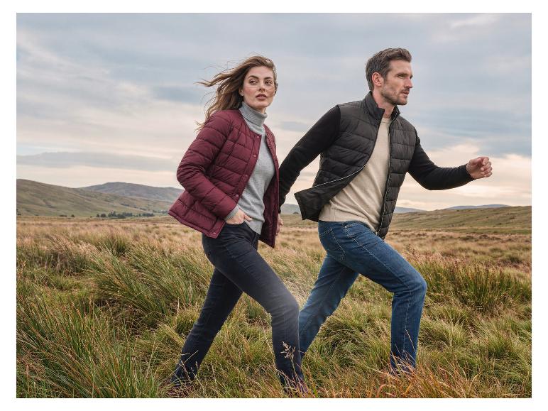 Mann und Frau in Naturlandschaft, tragen Steppjacken und Jeans.