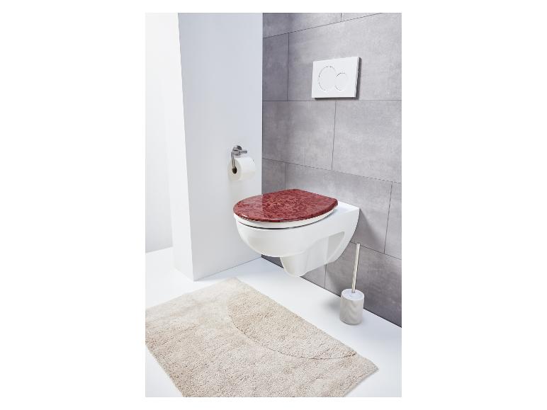 Toilette mit rotem Deckel und Teppich.