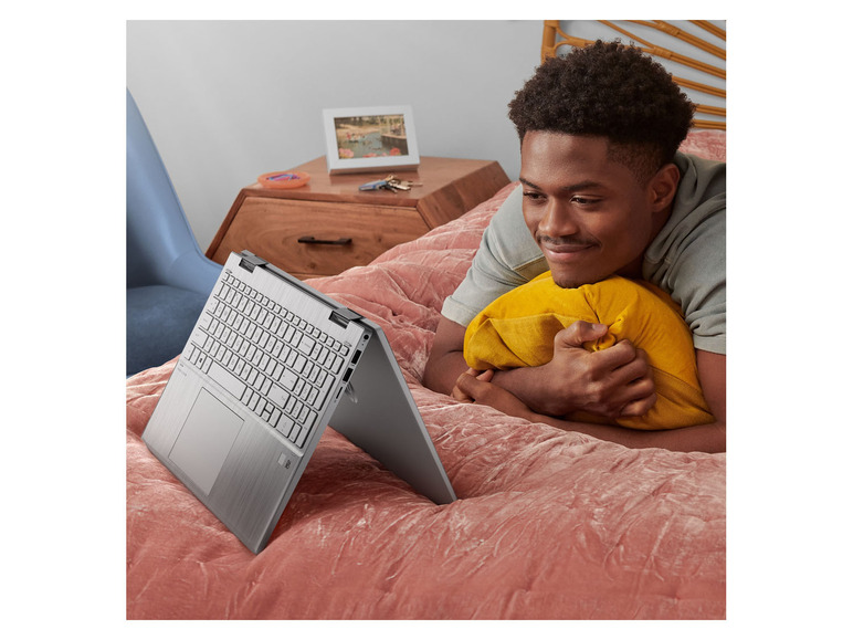 Ein Mann schaut im Bett auf einen Laptop.