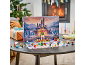 Kinder-Adventskalender mit Spielzeugschloss und Figuren auf einem Tisch vor dem Kamin.