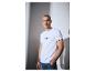 Mann in weißem T-Shirt und Jeans mit Hand in der Tasche, Text auf T-Shirt.