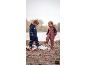 Zwei Kinder in Regenanzügen und Gummistiefeln spielen in einer Pfütze.