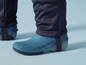 Blaue Gummistiefel mit schwarzen Bändern und schwarzen Hosenbeinen.