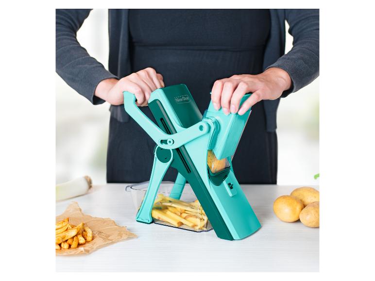 Frau benutzt einen Nicer Dicer, um Kartoffeln in der Küche zu schneiden, mit Pommes daneben.