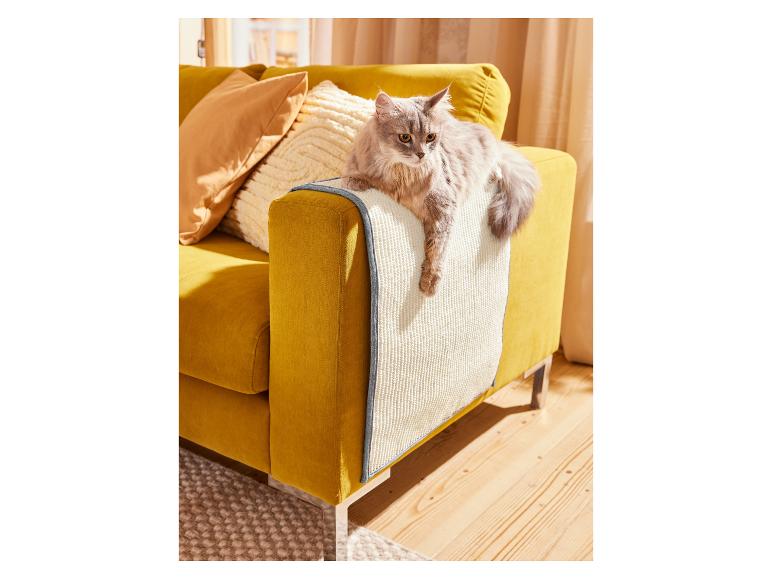 Eine graue Katze liegt auf einem gelben Sofa mit einem grauen und weißen Schutzbezug.