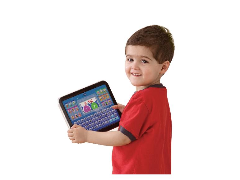 Lächelnder Junge hält ein Lern-Tablet mit Farbbildschirm und Tastatur.