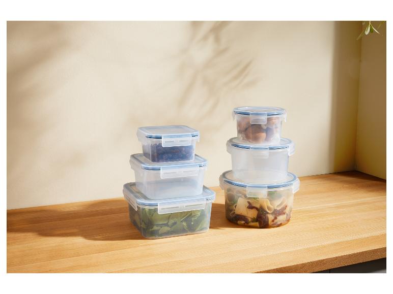 Transparente Vorratsbehälter für Lebensmittel, gestapelt auf einer Holztheke.