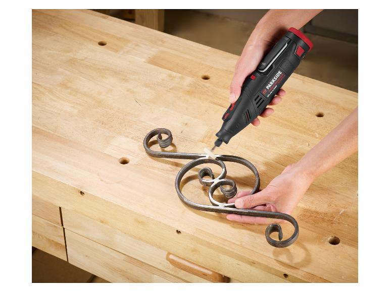 Eine Person verwendet ein Parkside Rotationswerkzeug, um ein Metallornament auf einer Werkbank zu schleifen.