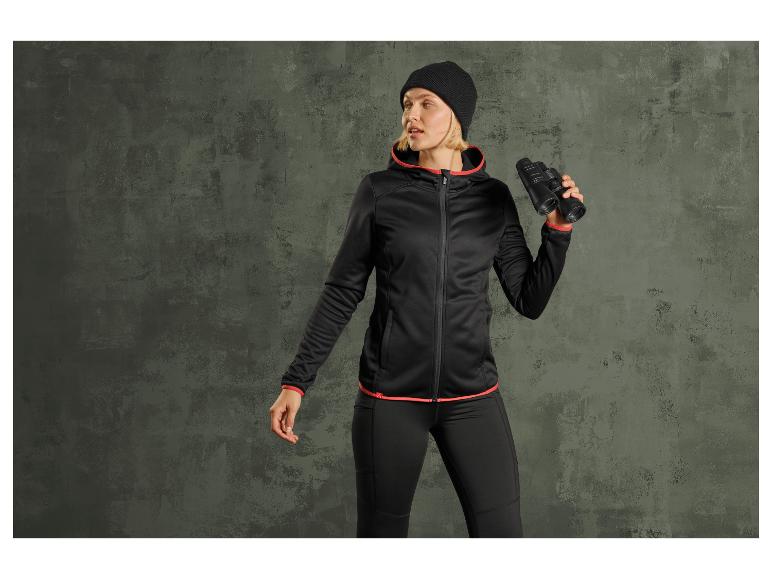 Frau in schwarzer Jacke und Hose hält ein Fernglas.