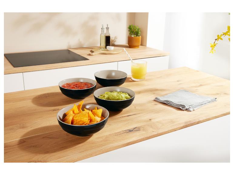 Drei Keramikschalen mit Snacks auf einem Holztisch.