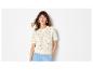Frau in cremefarbenem Kurzarm-Stricktop und hellblauer Hose.