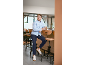 Mann in blauem Hemd und dunkelblauer Hose sitzt an einer Bar.