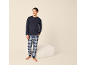 Mann in marineblauem Pyjama und karierter Hose, lächelnd.