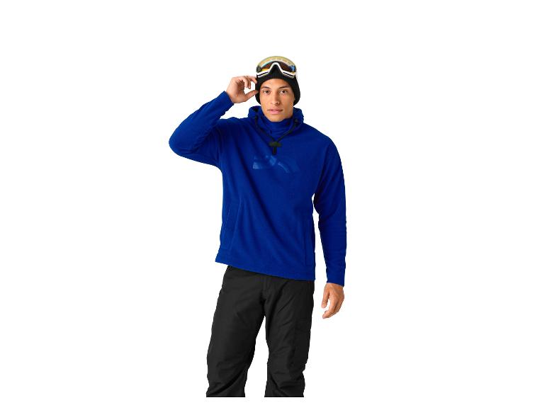 Mann in blauem Hoodie und schwarzer Hose, mit Skibrille auf dem Kopf.