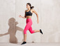 Eine Frau in rosa Sportleggings und einem schwarzen Sport-BH läuft während eines Trainings.