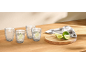 Vier Wassergläser mit Limette, frische Limetten und ein Küchentuch auf einem Holztisch.