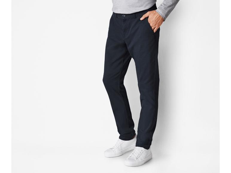 Ein Mann trägt eine dunkelblaue Hose und weiße Turnschuhe.