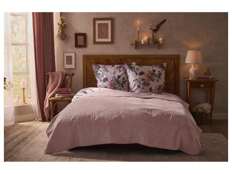 Ein gemütliches Schlafzimmer mit rosa Bett, Blumenkissen und rustikaler Dekoration.