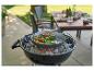 Gegrilltes Gemüse in einer Pfanne auf einem Holzkohlegrill, mit verschwommenem Gartenhintergrund.