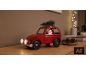 Rotes Spielzeugauto mit Weihnachtsmann und Tannenbaum auf einem Holzregal.